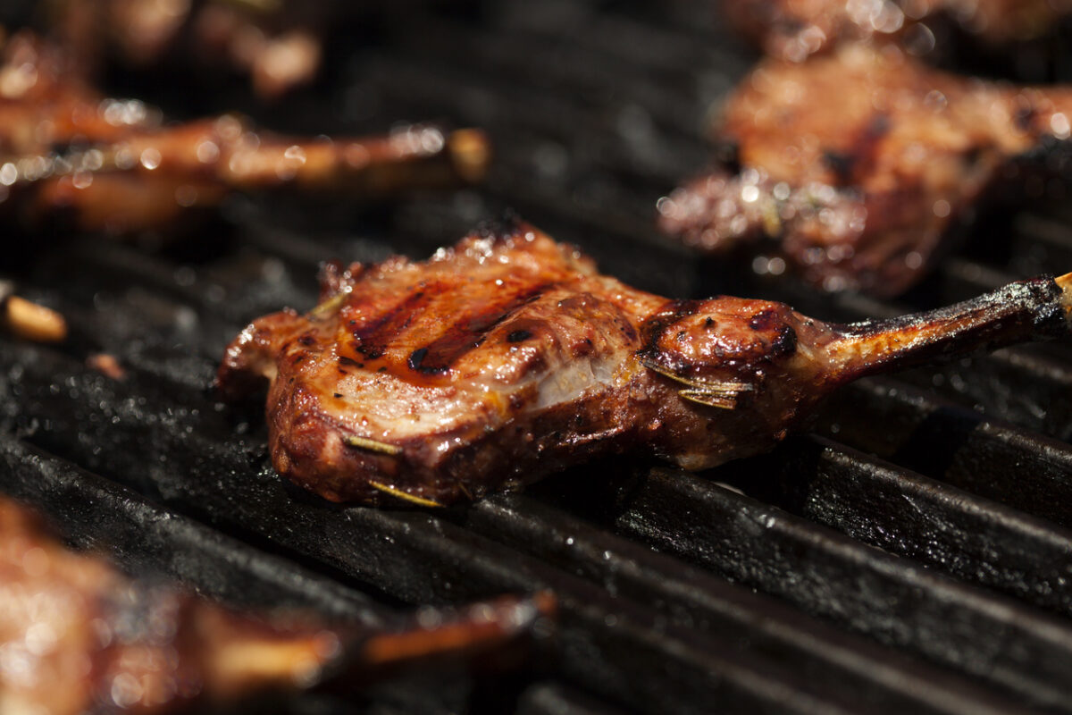 Closeup of grilling juicy lamb chops on grill grates. Narrow DOF.