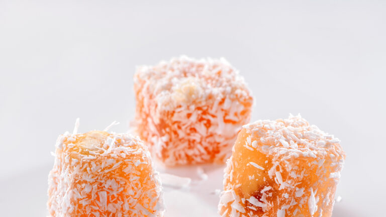 Turkish delight fruit-flavoured Rahat Lokum three pieces with coconut crumbs close-up on white background