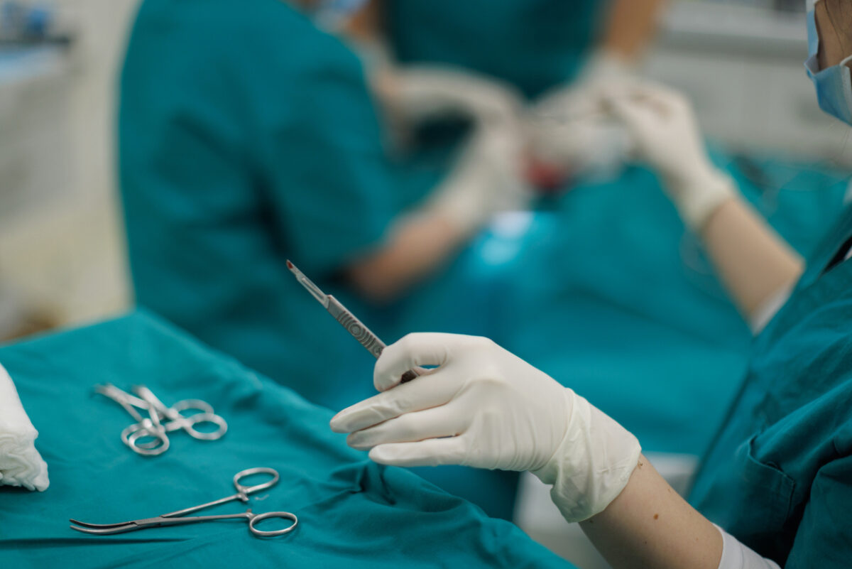 Nurse skillfully provides a scalpel to the surgeon during an ear reconstruction surgery. The precision and efficiency of the surgical team reflect the complexity and care required for this reconstructive procedure.