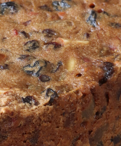 Stock photo showing a close-up view of a homemade Christmas fruitcake with nuts, sultanas and other dried fruit.