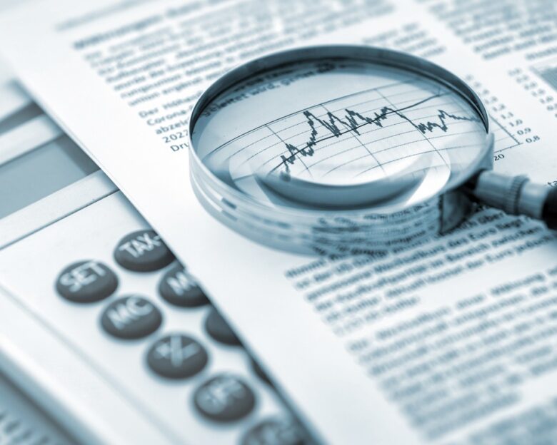 Magnifying glass, calculator and charts on paper symbolizing business and financial market. Blue toned image. studio shot in raw format taken with prime lens for best quality