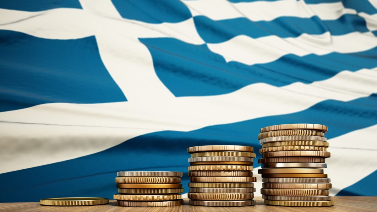 Rising stack of coins with Greek flag in the background. Economy, finance, interest rates concept.
