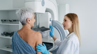 Senior woman having mammography scan at hospital with medical technician. Mammography procedure, breast cancer prevention