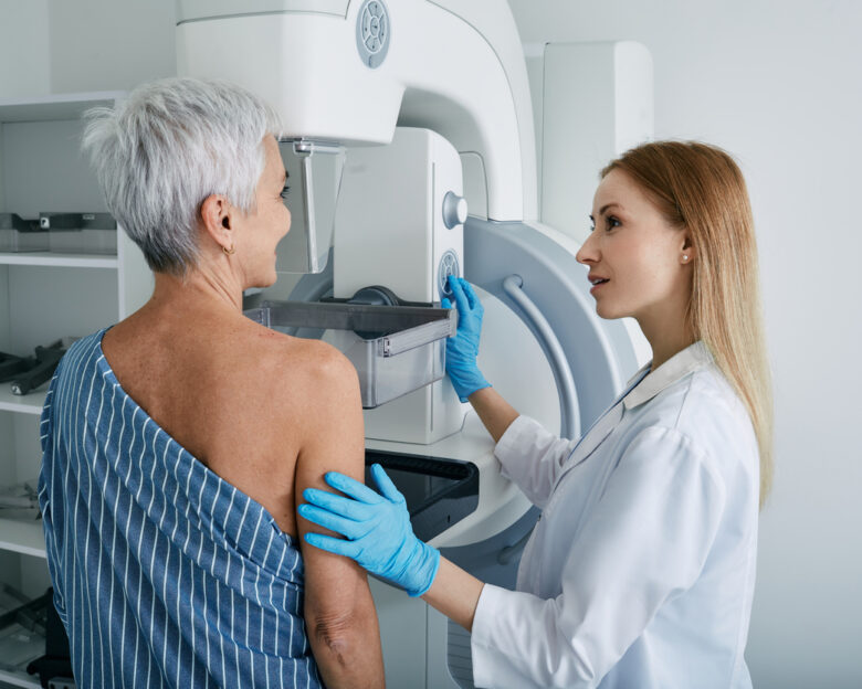 Senior woman having mammography scan at hospital with medical technician. Mammography procedure, breast cancer prevention