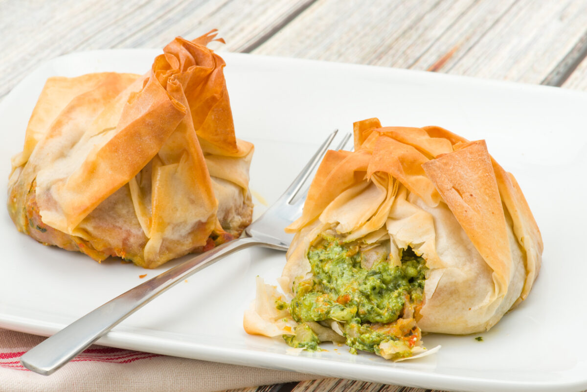 Two spinach and ricotta filo pastry parcels. Crisp and flaky filo pastry that has been brushed with butter for a golden finish - studio shot