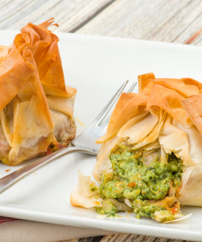 Two spinach and ricotta filo pastry parcels. Crisp and flaky filo pastry that has been brushed with butter for a golden finish - studio shot