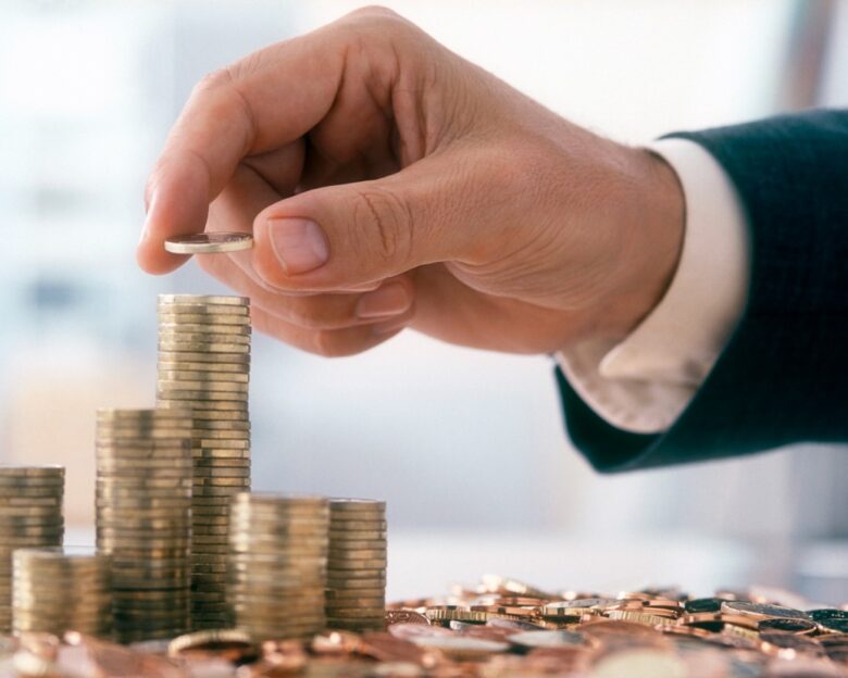 Hand of a mid adult man, wearing a siut, is stacking Euro coins.