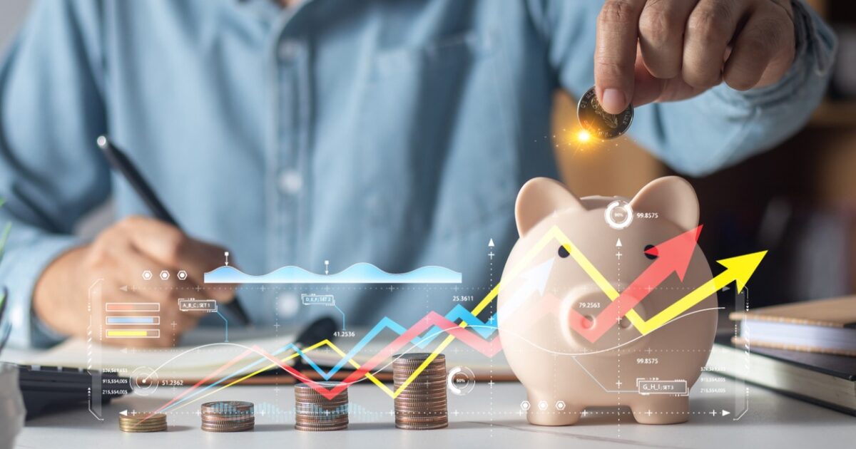 Man putting coins in piggy bank and taking notes in notebook money saving concept business