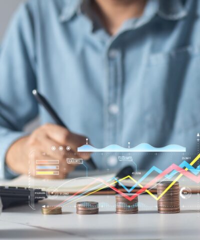 Man putting coins in piggy bank and taking notes in notebook money saving concept business