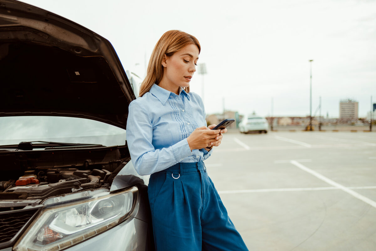 Stressed business woman calling roadside assistance after her car broke down. Accident and breakdowns with auto concept.