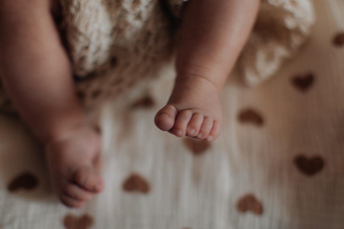 Sweet little feet of newborn baby on beige background, baby care and parenthood concept