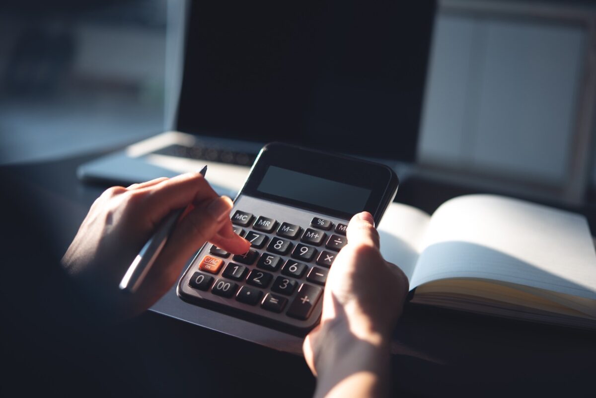 Close up, business woman working at office, using calculator to calculate company finance, accounting with laptop computer on table, budget management. Doing home finance, budgeting and tax calculation