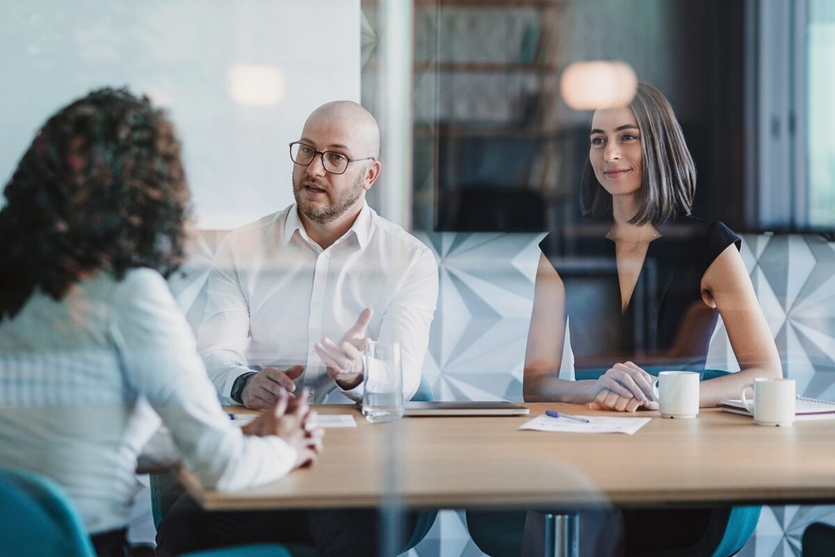 Group of business persons having a meeting behind a glass wall