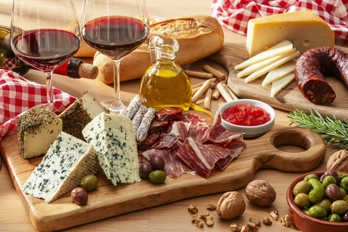 cheese and Serrano ham board, red wine and olives on wooden table