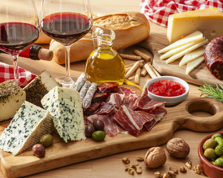 cheese and Serrano ham board, red wine and olives on wooden table