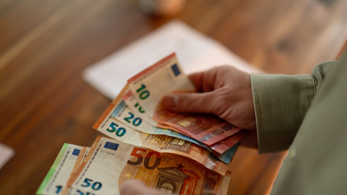 Close up of hands counting euro banknotes while planning household expenses and reviewing financial obligations.