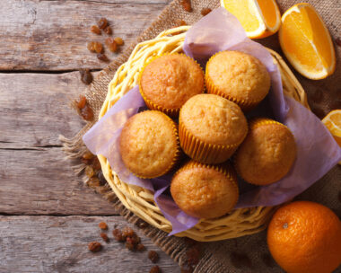 Citrus muffins in a basket and fresh oranges on an old table close-up. horizontal view from above