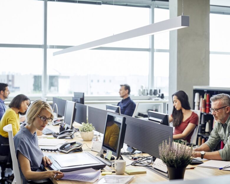 Business people working at desk. Male and female professionals are sitting by windows. Colleagues are sitting in textile industry.