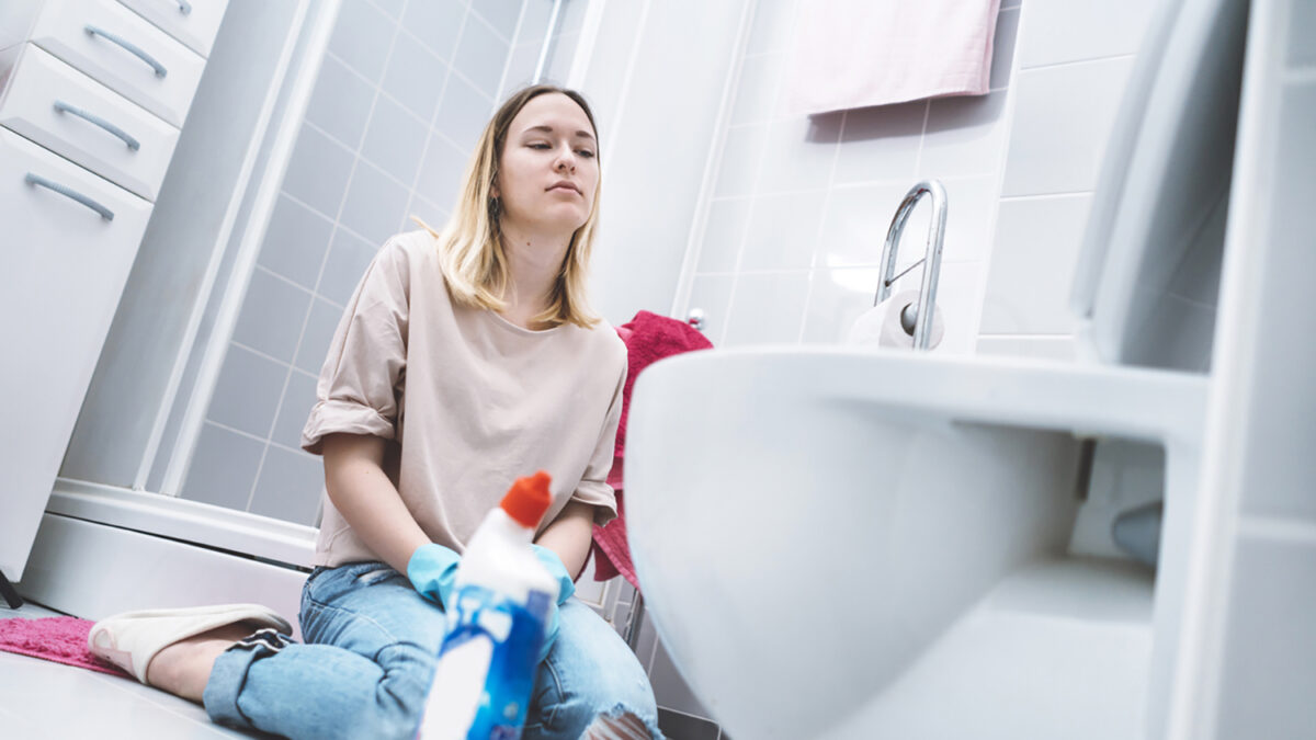 Young woman cleaning her bathroom, doing some laundry, cleaning the bathroom, cleaning with a yellow cloth, taking care of the cleanliness of her house, woman has blonde hair, clean house is beautiful, clothes are washed, woman putting clothes into the washing machine, girl wearing a pink shirt.