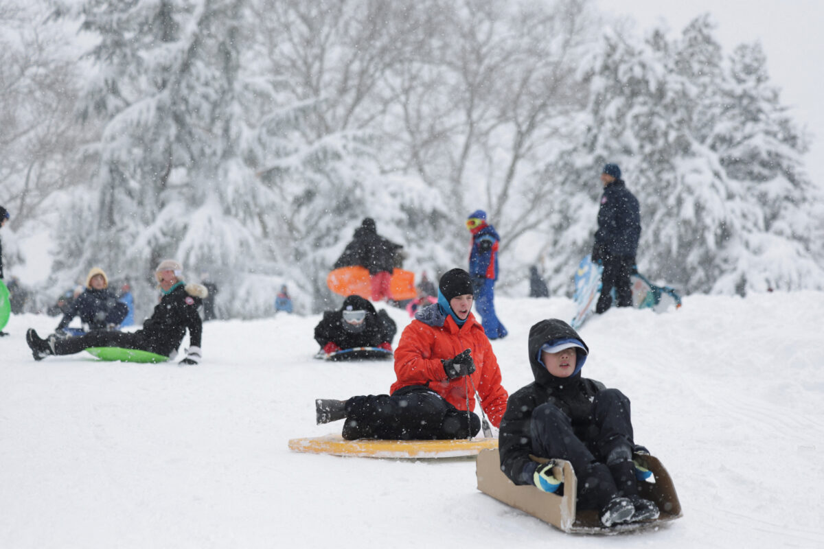 People sled in Central Park as snow falls during a winter storm in New York City, U.S., February 23, 2026. REUTERS/Jeenah Moon