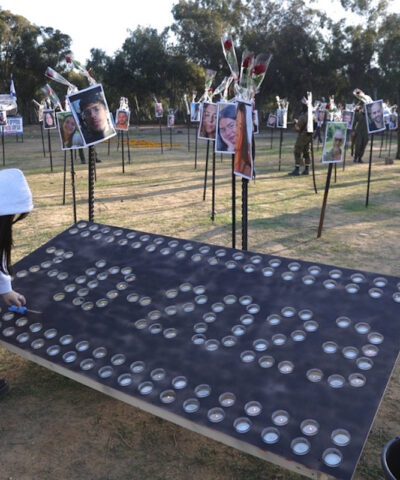 Μια γυναίκα ανάβει κεριά κοντά στις φωτογραφίες των θυμάτων της επίθεσης στο φεστιβάλ Nova, κοντά στα σύνορα της Γάζας στο νότιο Ισραήλ, στις 29 Νοεμβρίου 2023