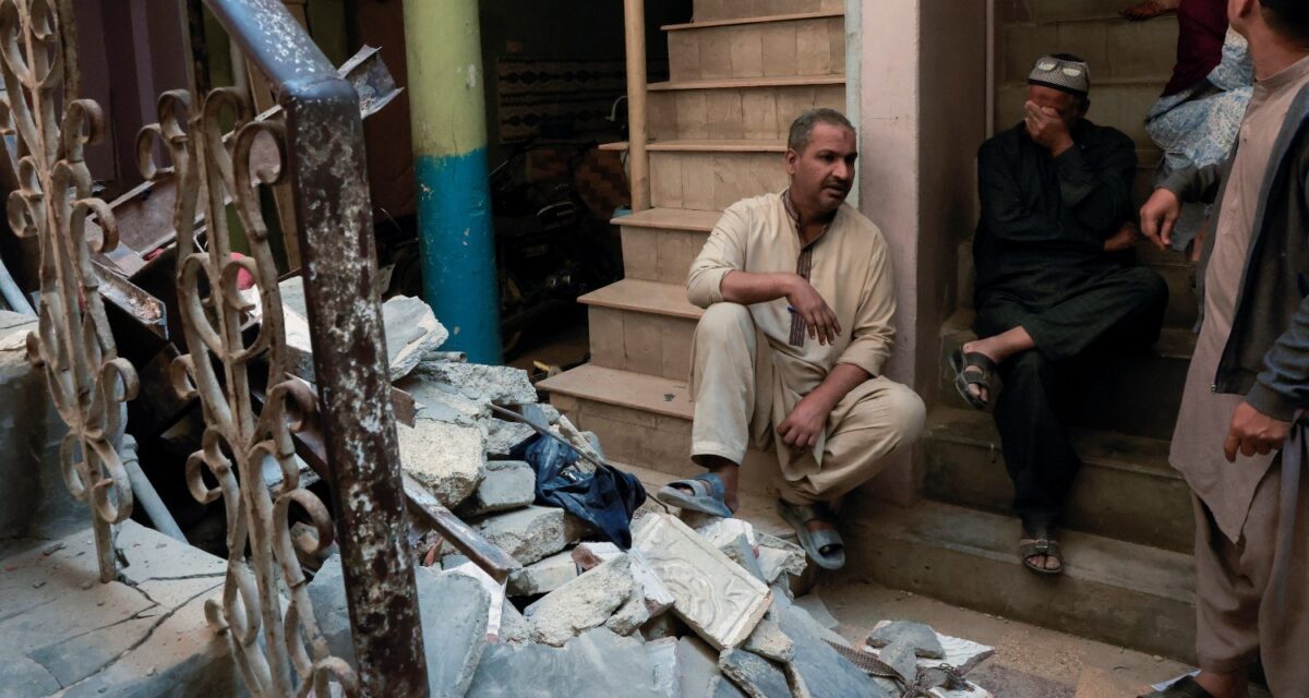 Residents sit beside debris after a gas cylinder blast caused a portion of a residential building to collapse in Karachi, Pakistan February 19, 2026. REUTERS/Akhtar Soomro