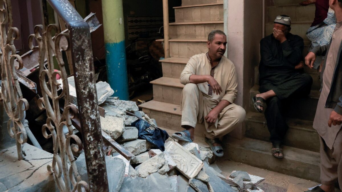 Residents sit beside debris after a gas cylinder blast caused a portion of a residential building to collapse in Karachi, Pakistan February 19, 2026. REUTERS/Akhtar Soomro