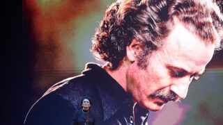 Η Άλκηστις Πρωτοψάλτη μπροστά από φωτογραφία του Νίκου Ξυλούρη