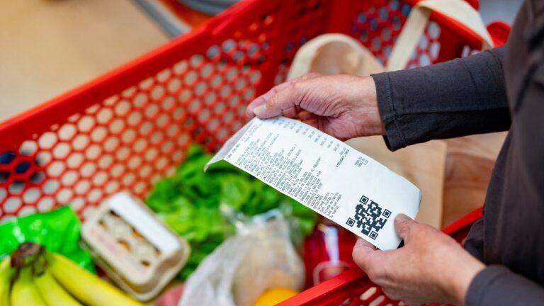 Close up of unrecognizable customer checking her receipt after purchasing groceries in the supermarket - Home shopping concepts