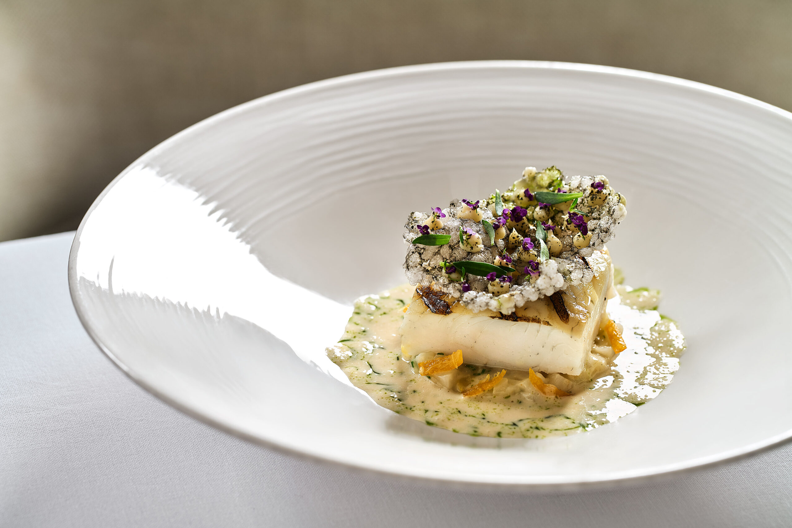 Το καλκάνι συνδυάζεται με μαϊντανόριζα, κράκερ ταπιόκας με φύκια και σάλτσα σαμπάνιας.