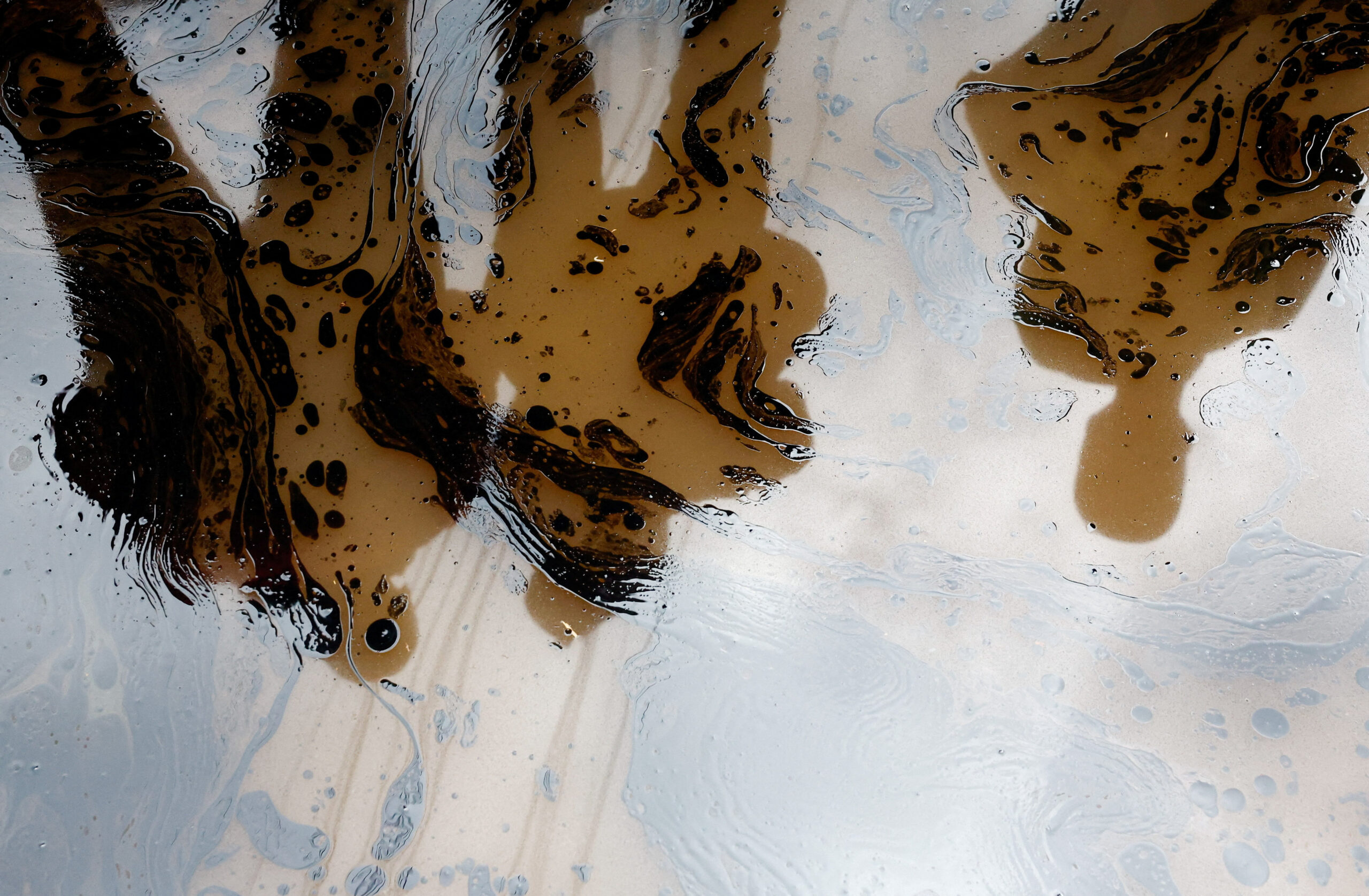 People stand near a trench polluted with petroleum waste from the wreckages of vehicles destroyed following heavy rainfall in the Grogan area, popular for automotive workshops and secondhand spare parts, in downtown Nairobi, Kenya, March 7, 2026. REUTERS/Thomas Mukoya       TPX IMAGES OF THE DAY