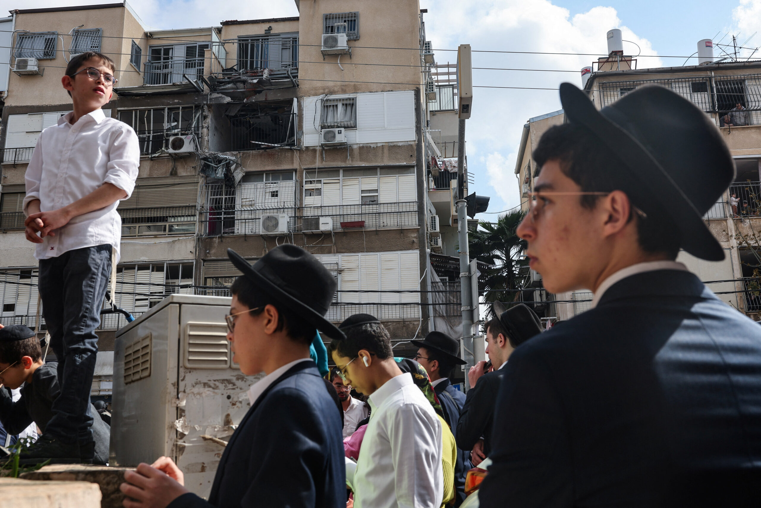 Aftermath of an Iranian projectile strike in central Israel People gather outside a damaged building following an Iranian projectile strike, amid the U.S.-Israeli conflict with Iran, in central Israel, March 15, 2026. REUTERS/Tyrone Siu