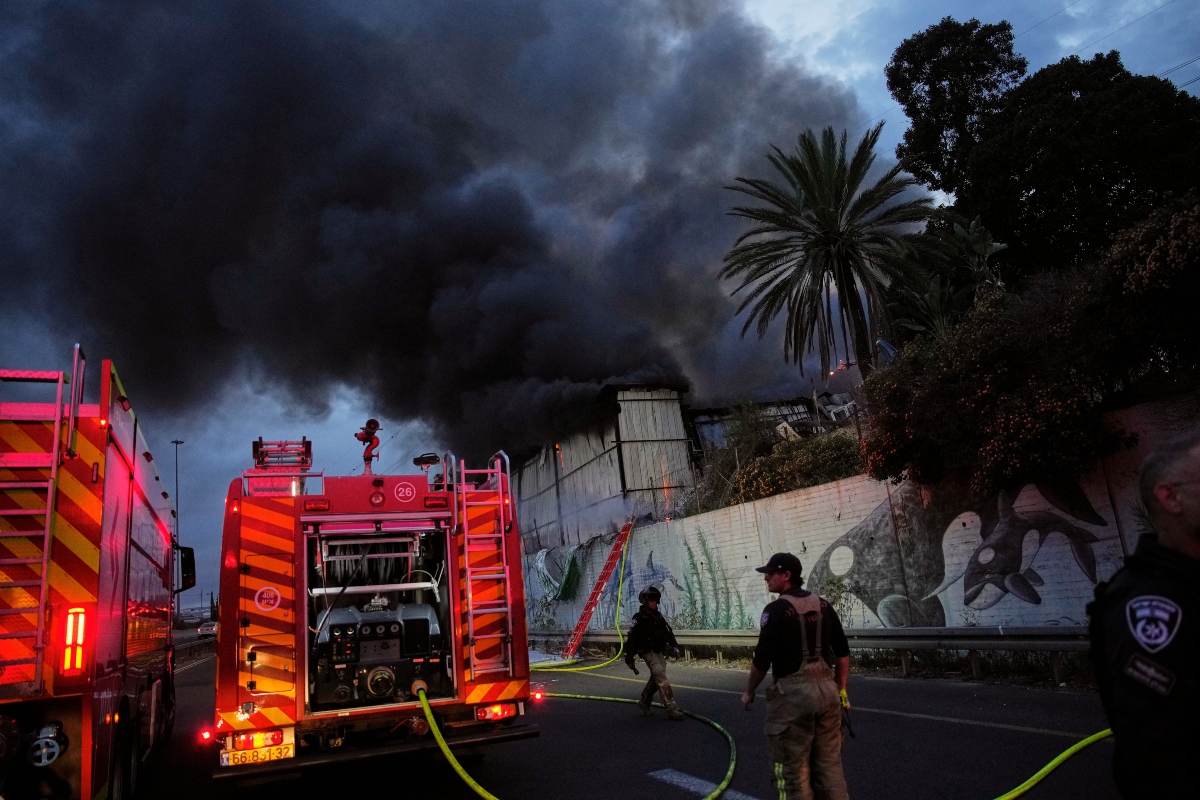 ap-telaviv Firefighters try to extinguish flames at the site of a direct hit by an Iranian missile strike in Holon, central Israel, Friday, March 13, 2026. (AP Photo/Ohad Zwigenberg)