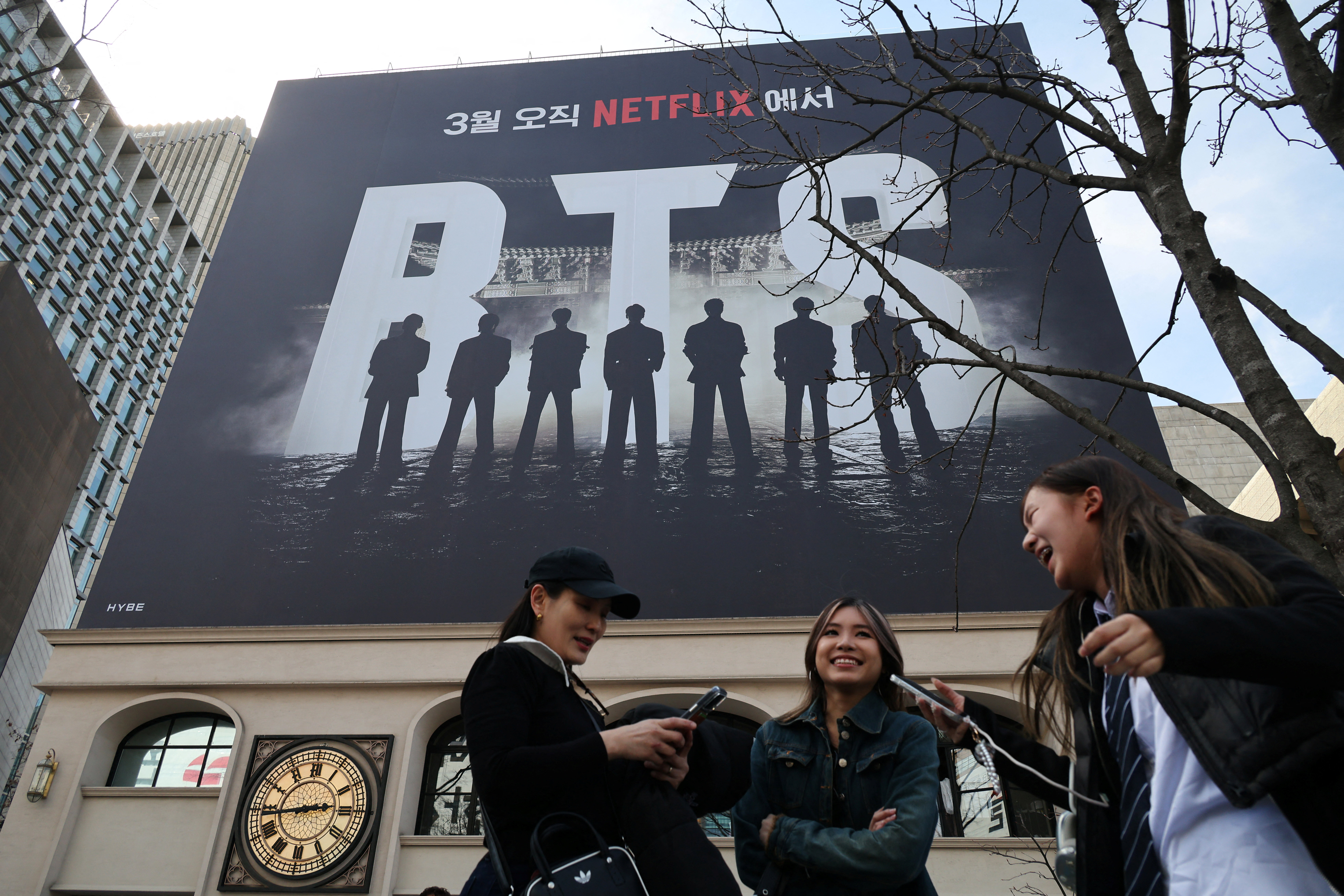 Fans of K-pop group BTS react after taking photographs with a huge banner promoting "BTS The Comeback Live Arirang" concert in central Seoul, South Korea, March 19, 2026. REUTERS/Kim Hong-Ji