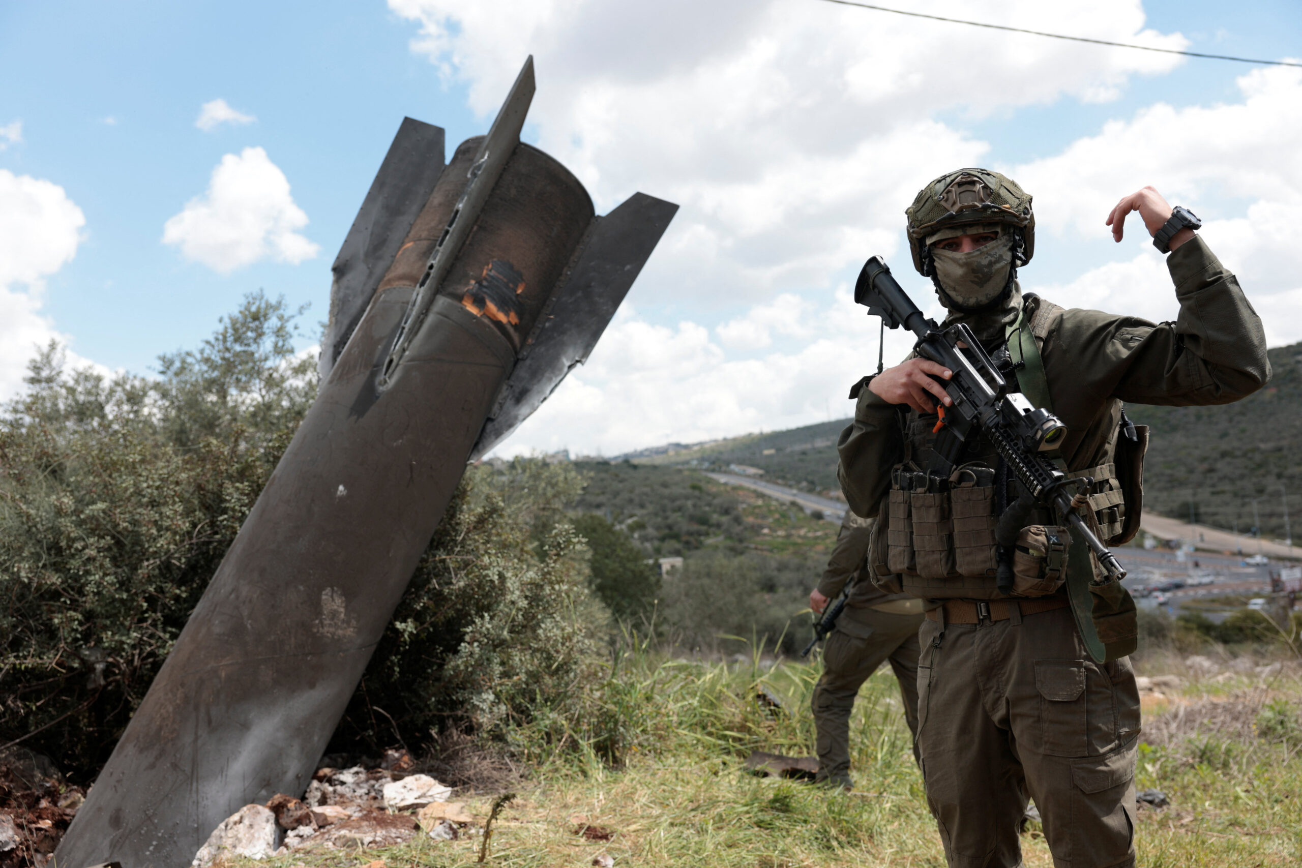 Remnants of a missile stuck in the ground found in Kifl Haris village, near Nablus in the Israeli-occupied West Bank An Israeli soldier gestures near remnants of a missile stuck in the ground found in Kifl Haris village, near Nablus in the Israeli-occupied West Bank, March 24, 2026. REUTERS/Mohammed Torokman
