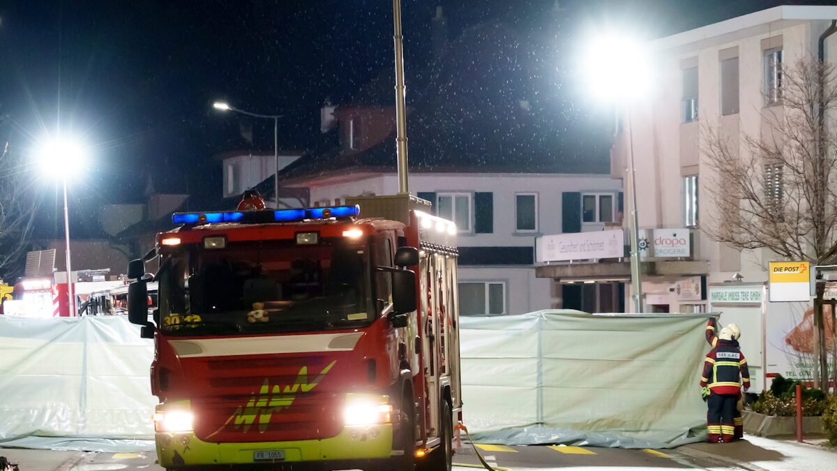 Πυροσβέστες και αστυνομικοί εγκαθιστούν φράγματα για να ασφαλίσουν την περιοχή όπου ένα ταχυδρομικό λεωφορείο πήρε φωτιά στο Kerzers της Ελβετίας.