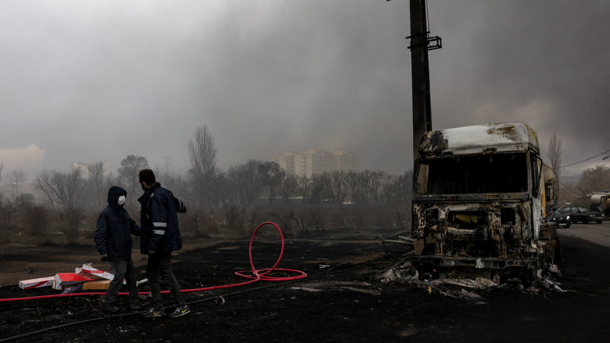 People stand near a destroyed vehicle as smoke rises after a reported strike on Shahran fuel tanks, amid the U.S.-Israeli conflict with Iran, in Tehran, Iran, March 8, 2026. Majid Asgaripour/WANA (West Asia News Agency) via REUTERS ATTENTION EDITORS - THIS PICTURE WAS PROVIDED BY A THIRD PARTY