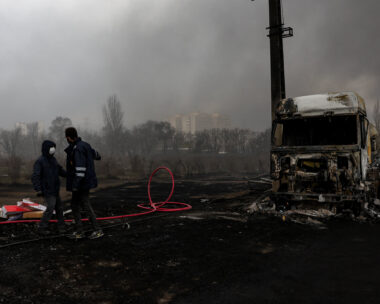 People stand near a destroyed vehicle as smoke rises after a reported strike on Shahran fuel tanks, amid the U.S.-Israeli conflict with Iran, in Tehran, Iran, March 8, 2026. Majid Asgaripour/WANA (West Asia News Agency) via REUTERS ATTENTION EDITORS - THIS PICTURE WAS PROVIDED BY A THIRD PARTY