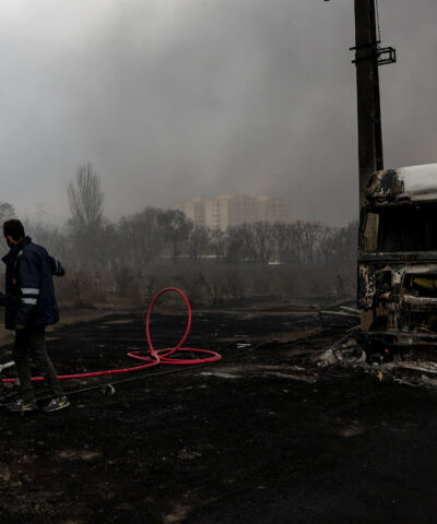 People stand near a destroyed vehicle as smoke rises after a reported strike on Shahran fuel tanks, amid the U.S.-Israeli conflict with Iran, in Tehran, Iran, March 8, 2026. Majid Asgaripour/WANA (West Asia News Agency) via REUTERS ATTENTION EDITORS - THIS PICTURE WAS PROVIDED BY A THIRD PARTY