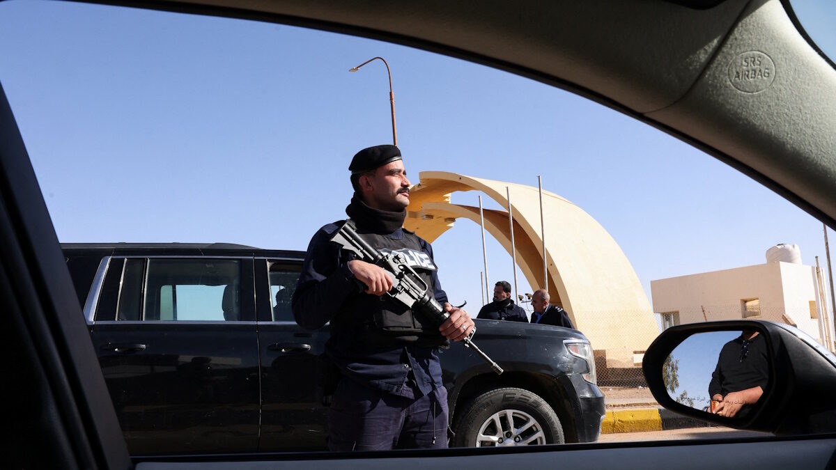 Ένας αστυνομικός στέκεται φρουρός καθώς πολίτες, εγκαταλείπουν το Ιράκ μέσω της συνοριακής διάβασης Καράμε με την Ιορδανία, μετά το κλείσιμο των αεροδρομίων στο Ιράκ λόγω της κλιμάκωσης των περιφερειακών εντάσεων, εν μέσω της σύγκρουσης των ΗΠΑ και του Ισραήλ με το Ιράν