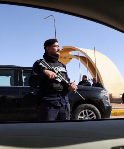 Ένας αστυνομικός στέκεται φρουρός καθώς πολίτες, εγκαταλείπουν το Ιράκ μέσω της συνοριακής διάβασης Καράμε με την Ιορδανία, μετά το κλείσιμο των αεροδρομίων στο Ιράκ λόγω της κλιμάκωσης των περιφερειακών εντάσεων, εν μέσω της σύγκρουσης των ΗΠΑ και του Ισραήλ με το Ιράν