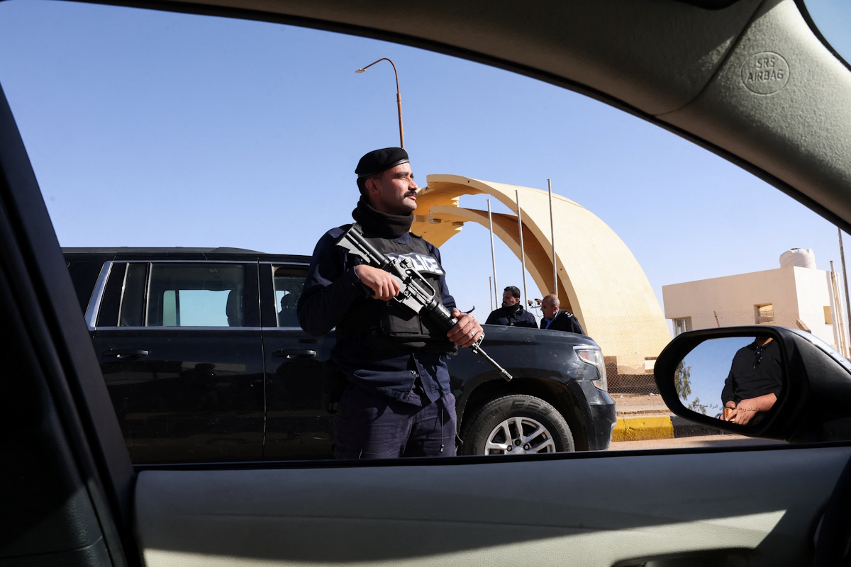 Ένας αστυνομικός στέκεται φρουρός καθώς πολίτες, εγκαταλείπουν το Ιράκ μέσω της συνοριακής διάβασης Καράμε με την Ιορδανία, μετά το κλείσιμο των αεροδρομίων στο Ιράκ λόγω της κλιμάκωσης των περιφερειακών εντάσεων, εν μέσω της σύγκρουσης των ΗΠΑ και του Ισραήλ με το Ιράν