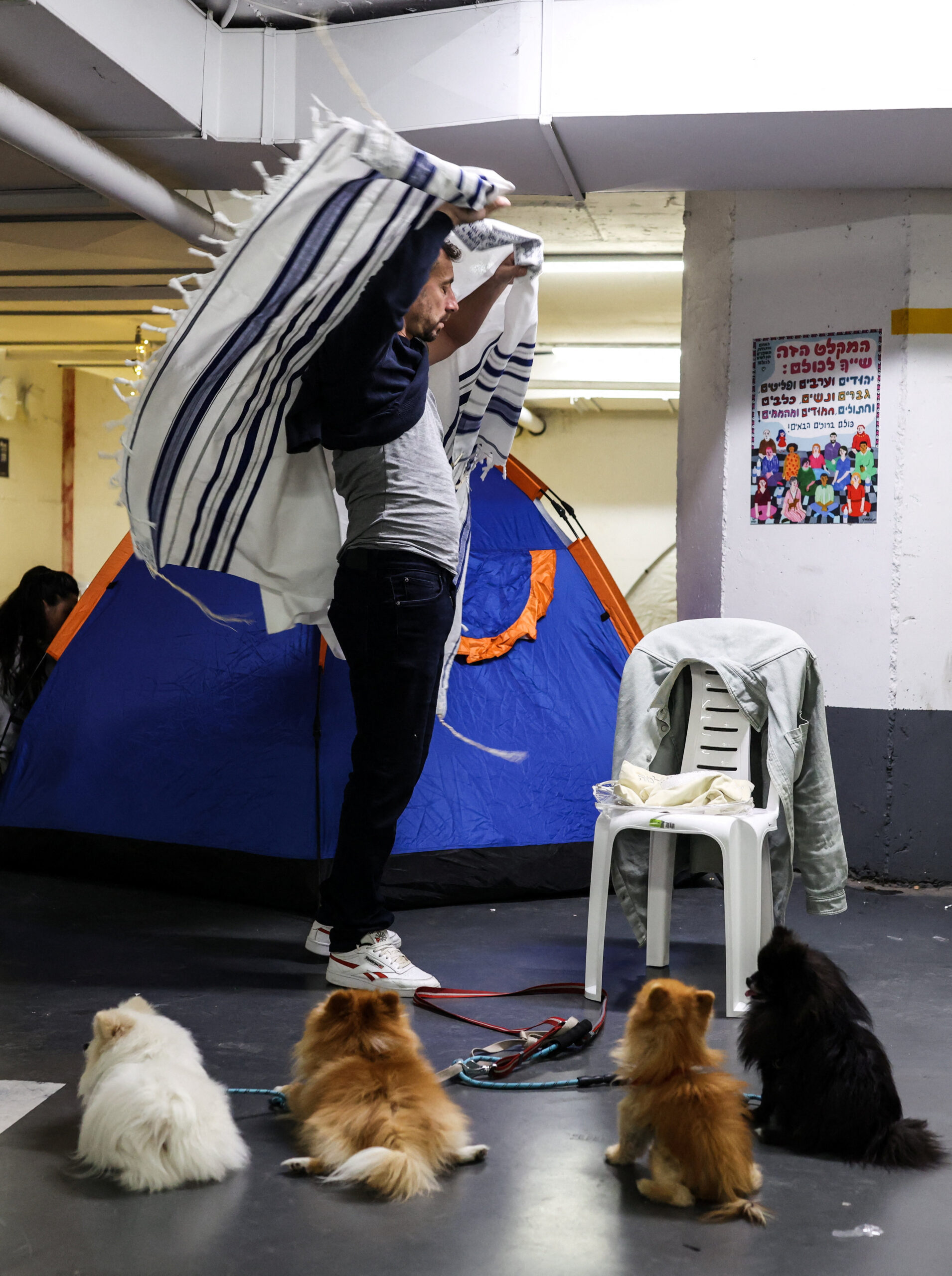 A man adjusts his Tallit, a Jewish prayer shawl during morning prayers in an underground car park that functions as a bomb shelter, amid the U.S.-Israel conflict with Iran and during the Jewish holiday of Purim, in Tel Aviv, Israel March 3, 2026. REUTERS