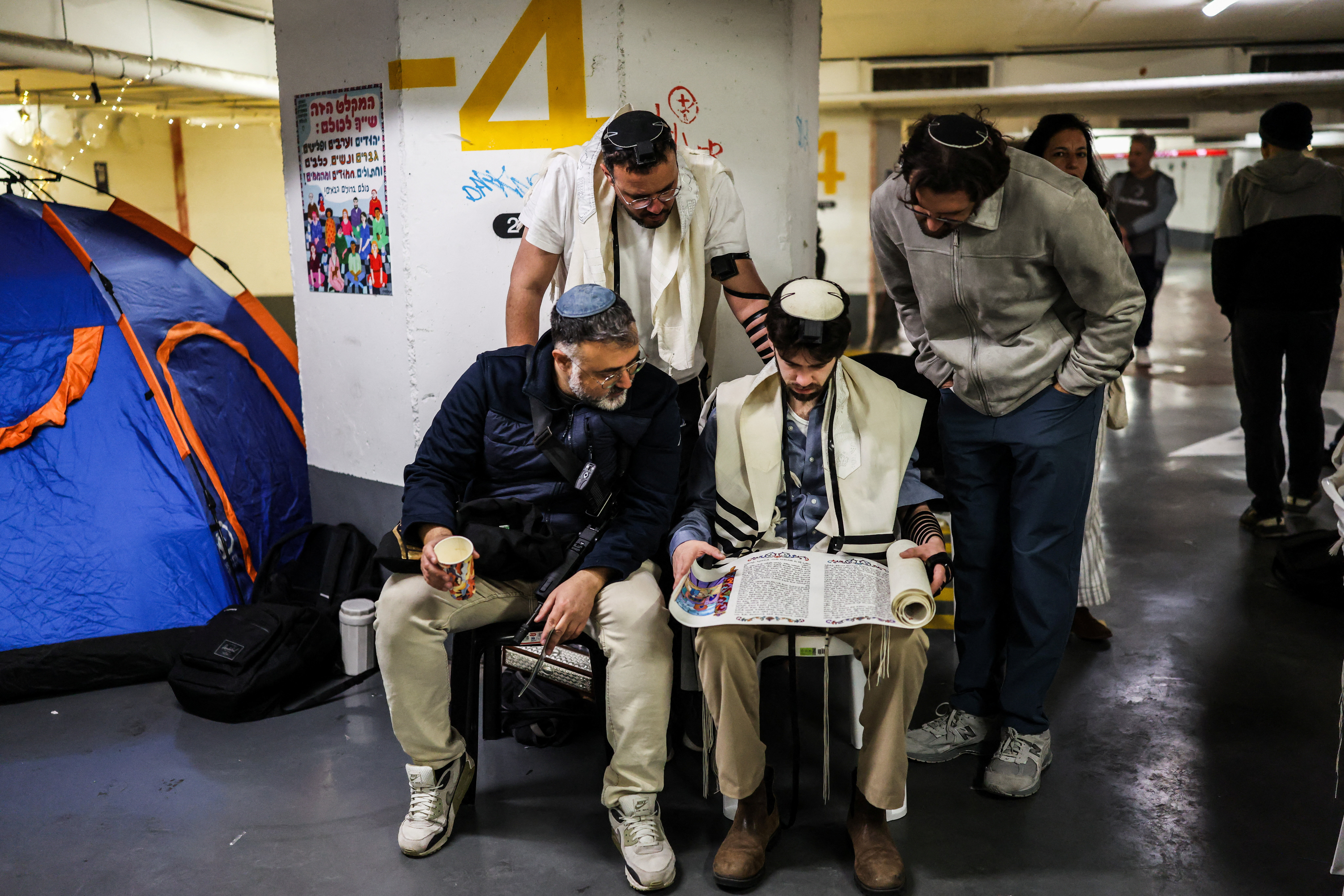 Men read from the Book of Esther in an underground car park that functions as a bomb shelter, during the Jewish holiday of Purim, a celebration of the Jews' salvation from genocide in ancient Persia, as recounted in the Book of Esther, amid the U.S.-Israel conflict with Iran, in Tel Aviv, Israel March 3, 2026. REUTERS