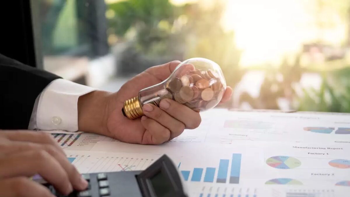 Hand of businessman hold light bulb with coin. Concept of Cost reduction and Reduce energy