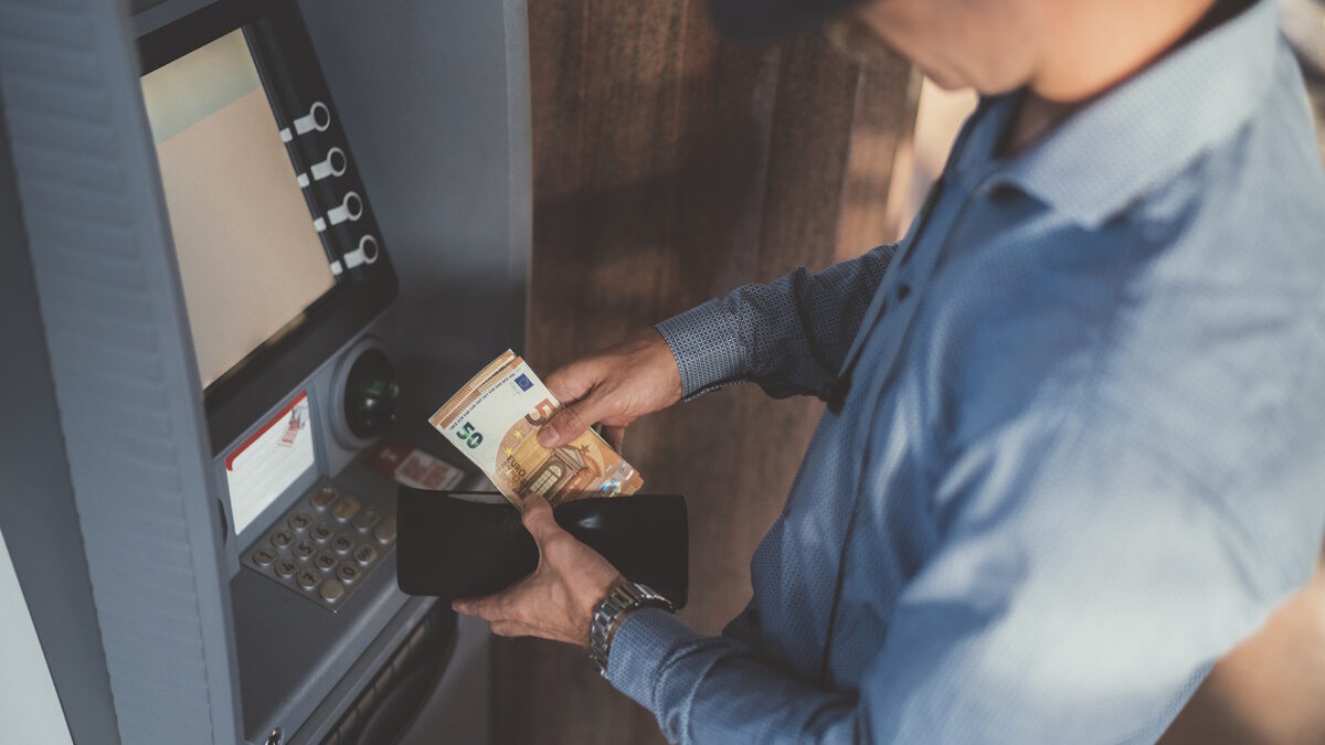 Close up of businessman withdrawing money and putting in the wallet