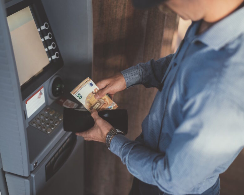 Close up of businessman withdrawing money and putting in the wallet