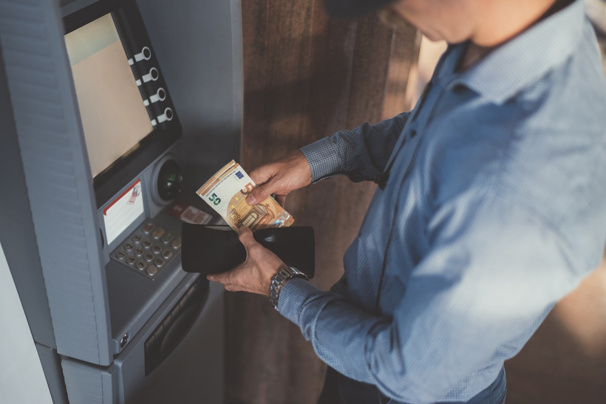 Close up of businessman withdrawing money and putting in the wallet