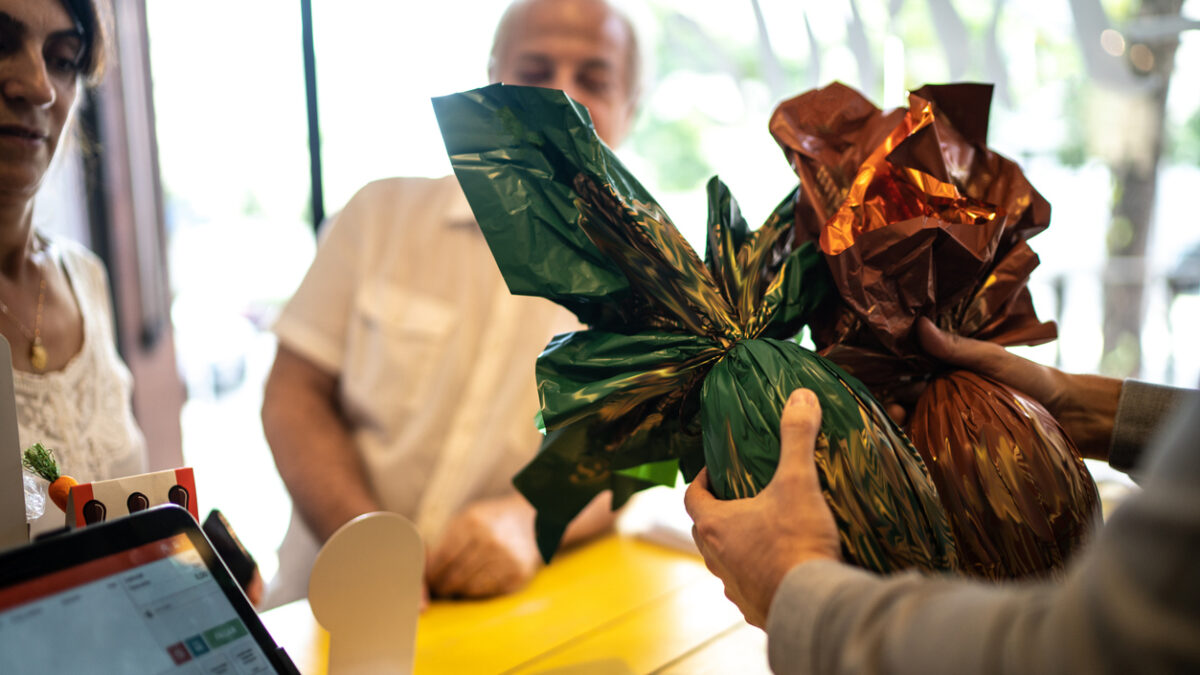 Owner selling easter egg for a senior couple in a store