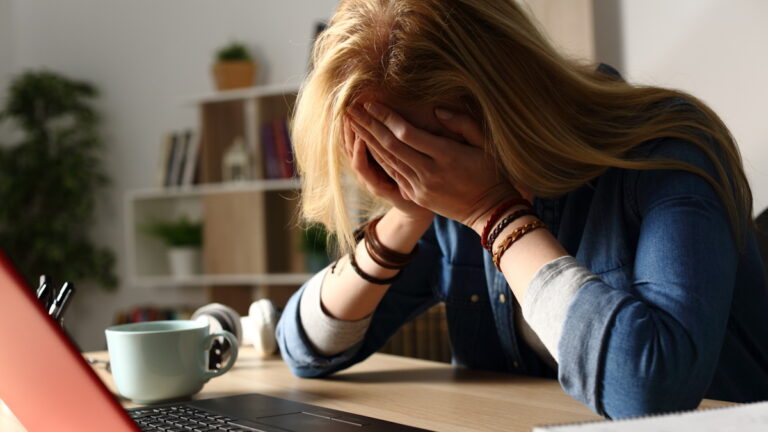 Close up of sad student receiving bad news on laptop sitting on a desk at home at night